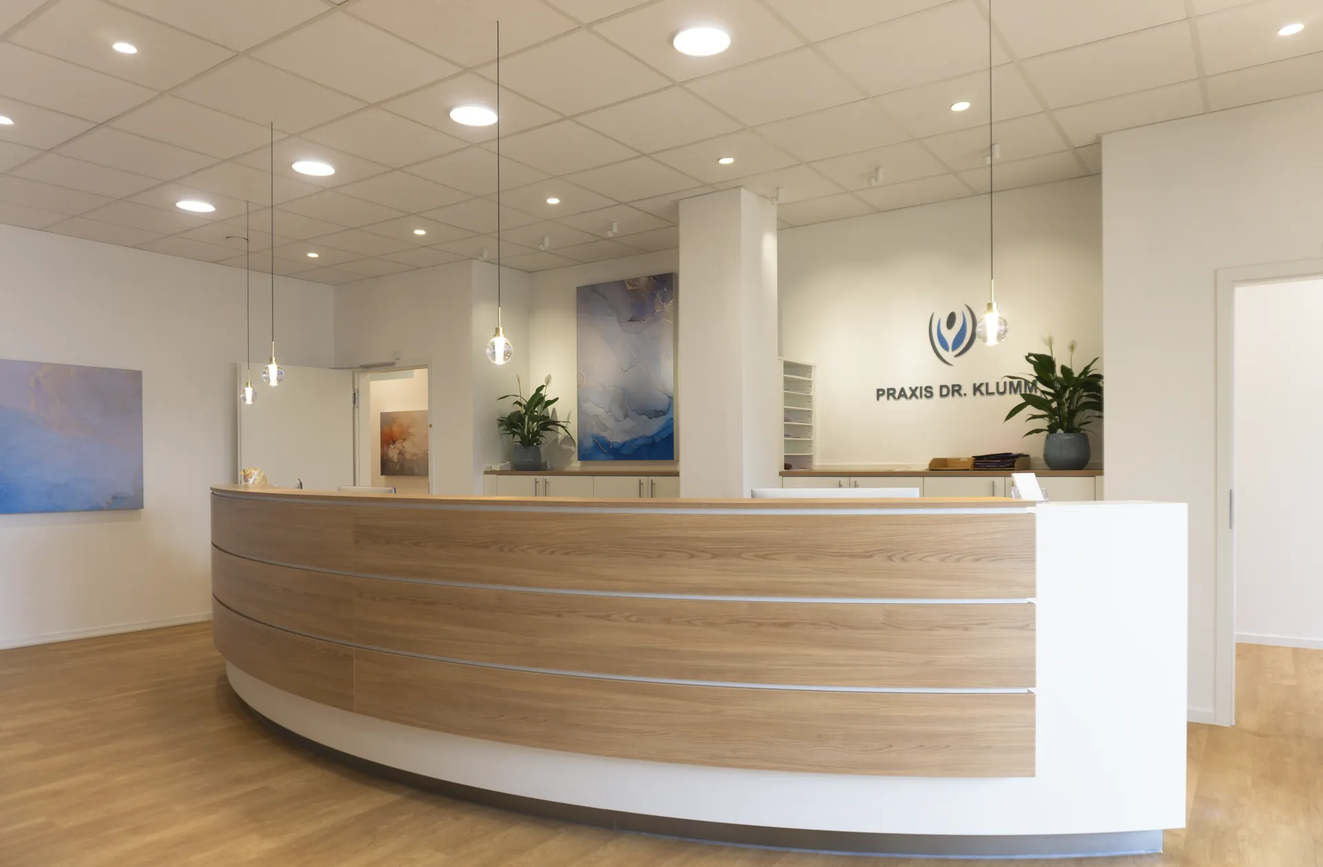 Eingangsbereich einer Praxis, beleuchtet mit Kugelpendelleuchte Alaska, Downlight Stram und Downlight Buddy.